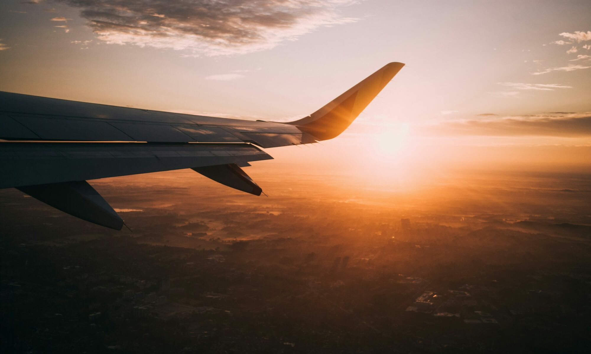 Avion survolant un paysage au coucher de soleil, symbolisant l’évasion et le voyage vers des destinations inspirées de films et séries.